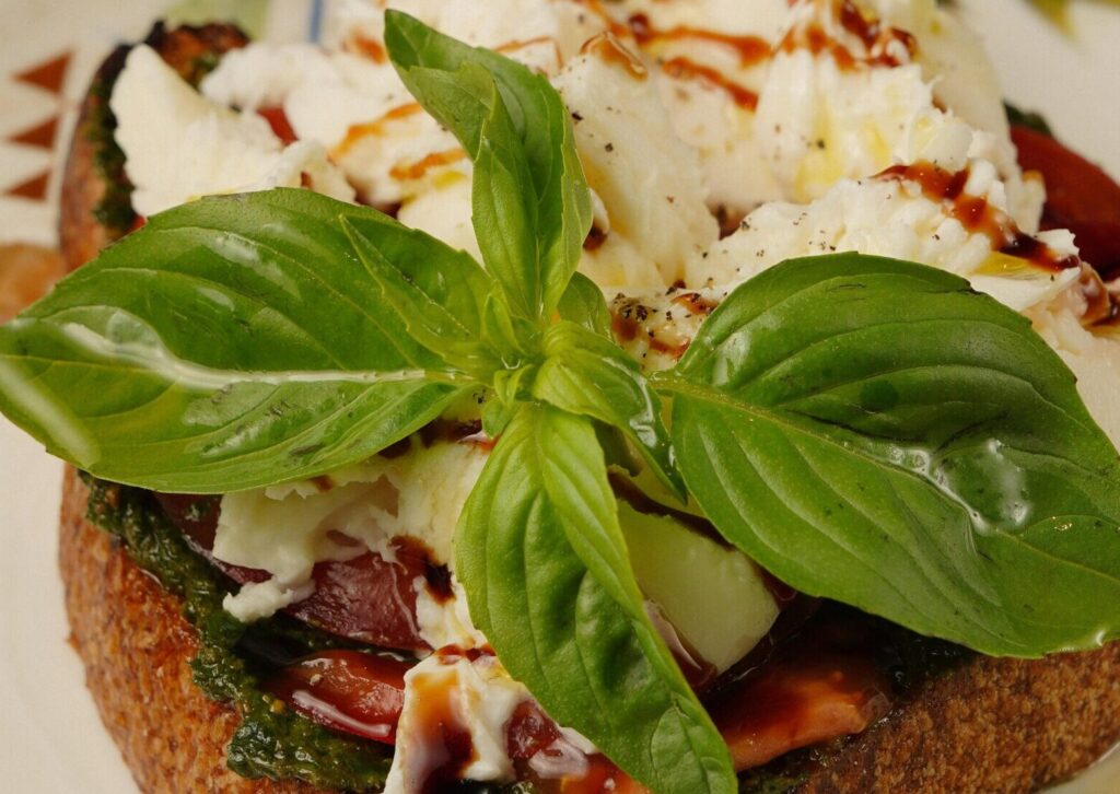 pexels-photo-25650517-25650517 Appetizing bruschetta topped with fresh basil, burrata, and balsamic glaze on a decorative plate.